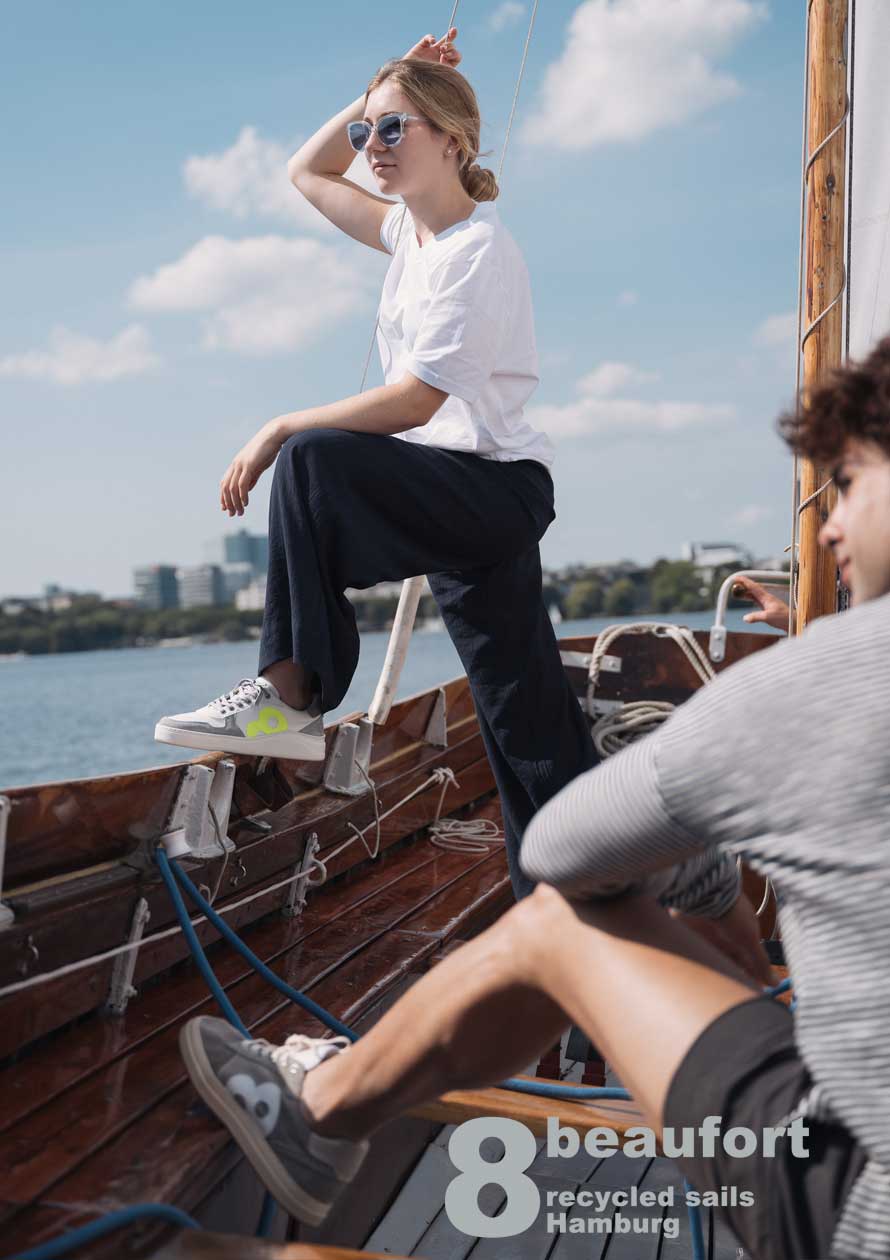 Eine Frau steht auf einem Segelschiff und hat einen Sneaker an.